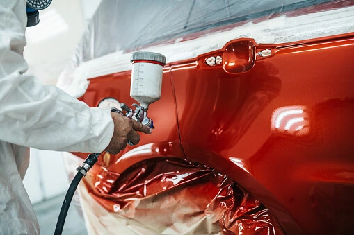 Pintor pintando vehículo en el horno de pintura de G & T Automotriz en La Molina - Lima - Perú